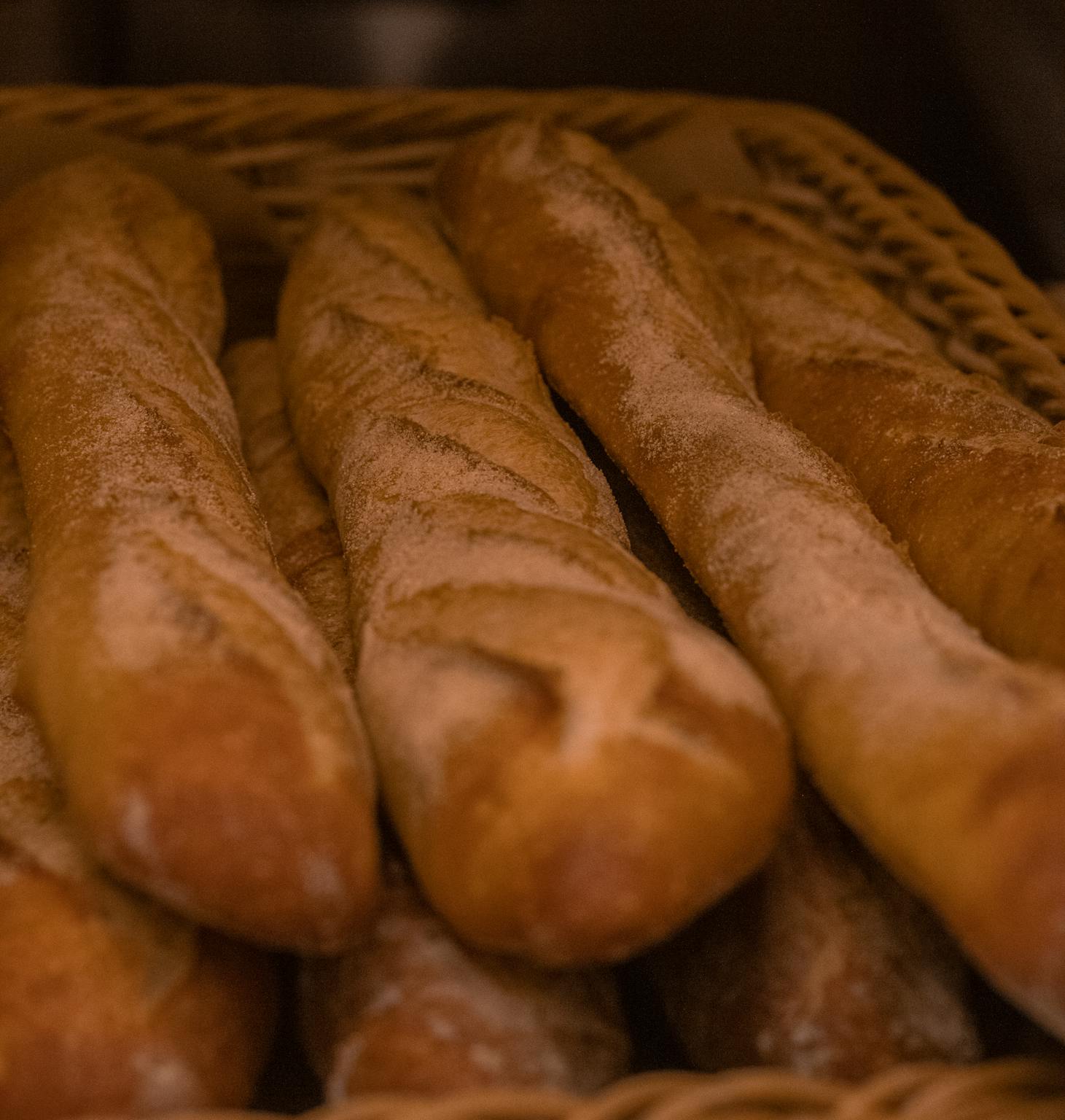 Close-up of freshly baked baguettes in a woven basket, showcasing artisanal bread.