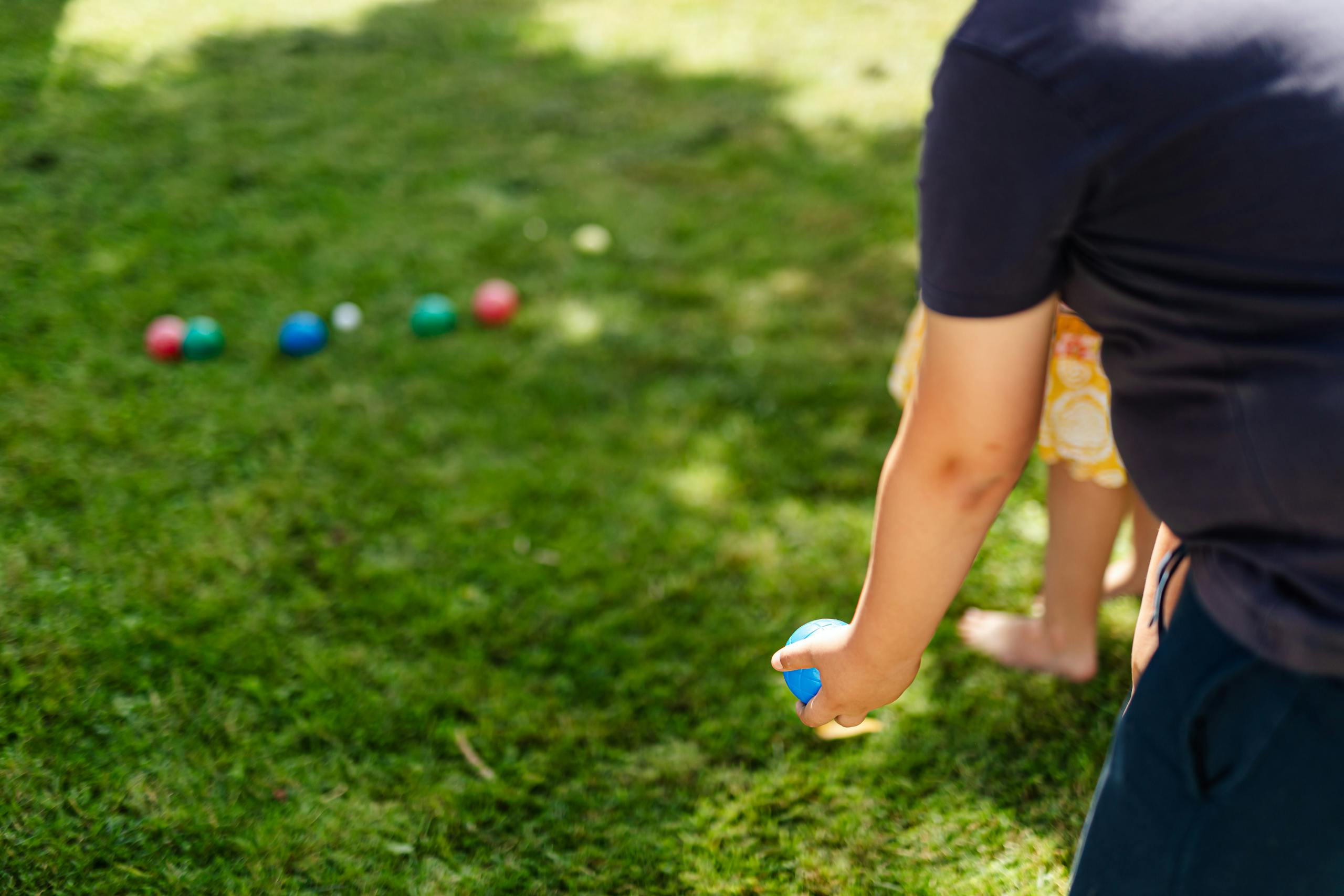 Father and daughter enjoy a fun game of bocce ball in a sunny backyard.